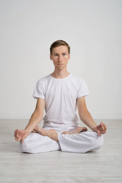 Молодой человек медитирует в позе Лотоса на полу — стоковое фото