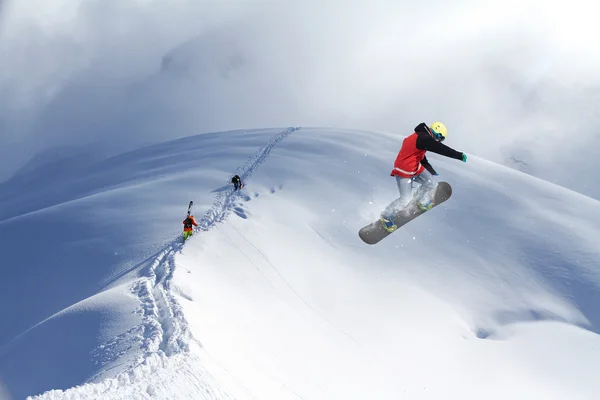 Snowboarder, ugrás a hegyekben. Extrém sport. — Stock Fotó