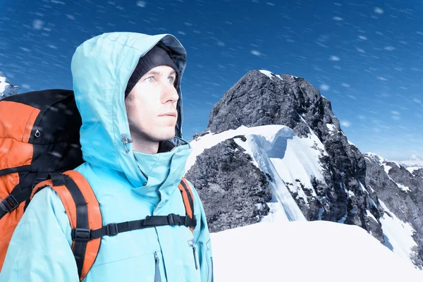 The mountaineer looks at the peak, standing against a winter mountain landscape. — Stock Photo, Image