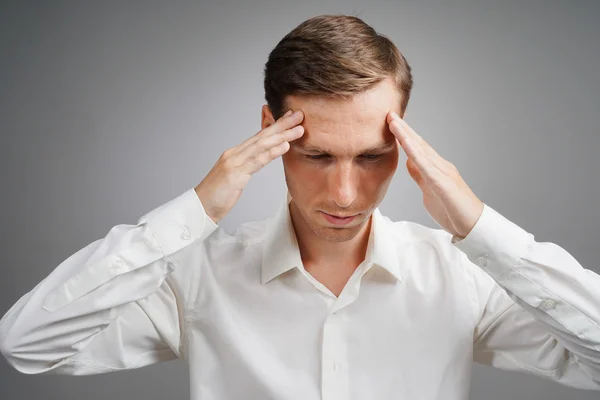 Young man in white shirt thinking or experiencing headaches. — Stock Photo, Image