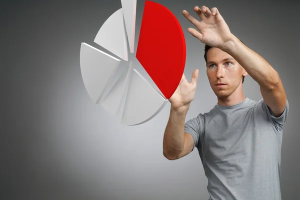 Man in t-shirt working with pie chart on grey background. — Stock Photo, Image