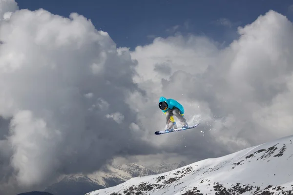 Snowboarder che salta in montagne invernali innevate — Foto Stock