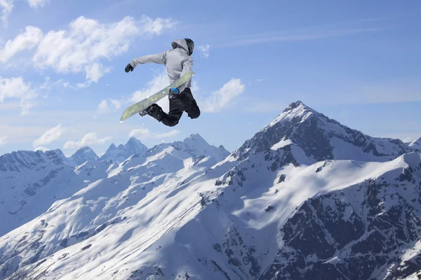 Snowboardista skákání v zasněžených zimních horách — Stock fotografie