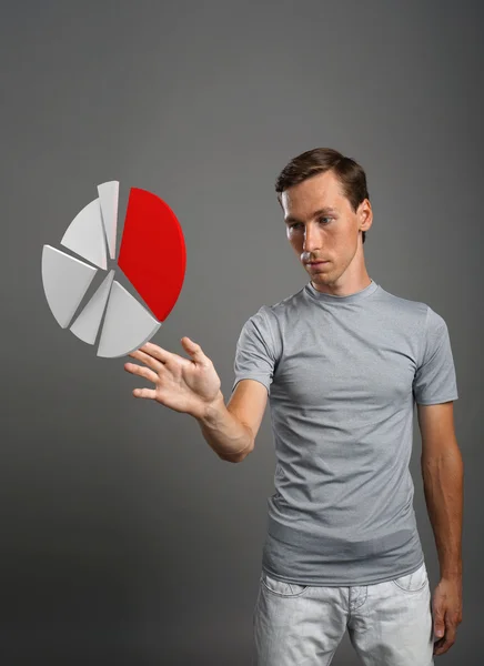 Uomo in t-shirt lavorante con grafico a torta su fondo grigio . — Foto Stock