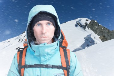 Dağcı adam arka plan yüksek dağlarda kamera bakıyor. Yakın çekim portre.