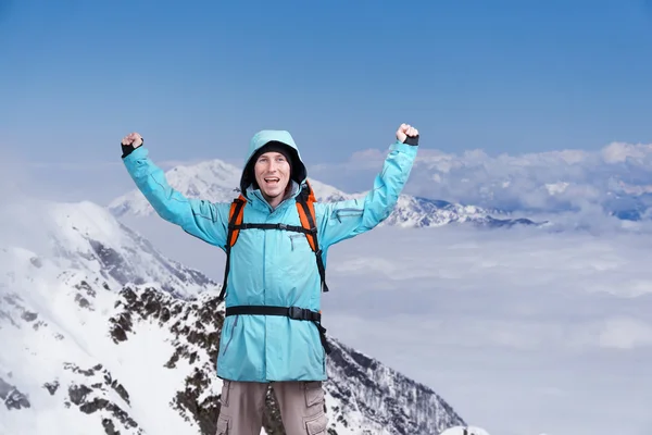 調達の腕を持つ男は幸せの男性登山家。背景高山に雲の上 . — ストック写真