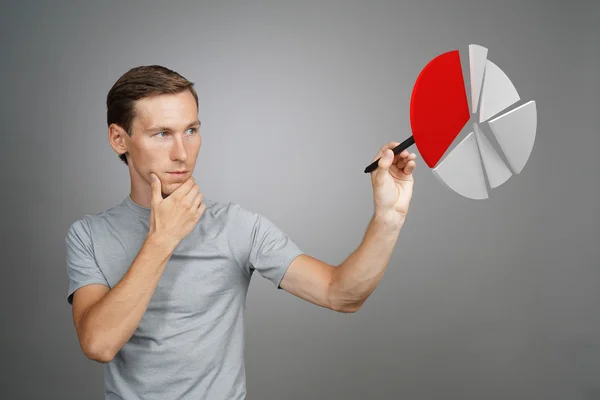 Mannen i t-shirt arbetar med cirkeldiagram på grå bakgrund. — Stockfoto