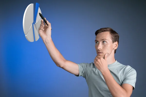 Hombre en camiseta trabajando con gráfico circular sobre fondo azul . — Foto de Stock