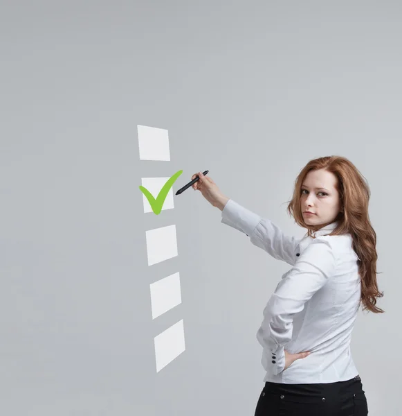 Joven mujer de negocios revisando la casilla de la lista. Fondo gris . — Foto de Stock