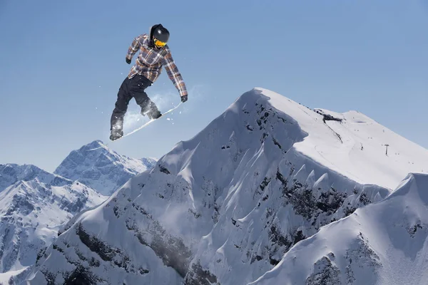 Cavaleiro de snowboard pulando em montanhas. Esporte de freeride de snowboard extremo. — Fotografia de Stock