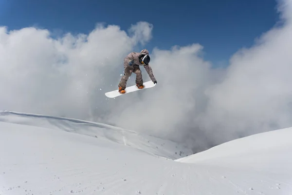 Un snowboarder saltando en las montañas. Snowboard, deporte extremo invernal. —  Fotos de Stock