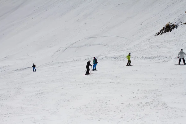 Skiers and snowboarders going down the slope at ski resort. — Stock Photo, Image