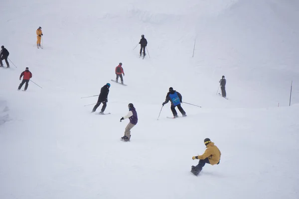 Skiers and snowboarders going down the slope. — Stock Photo, Image