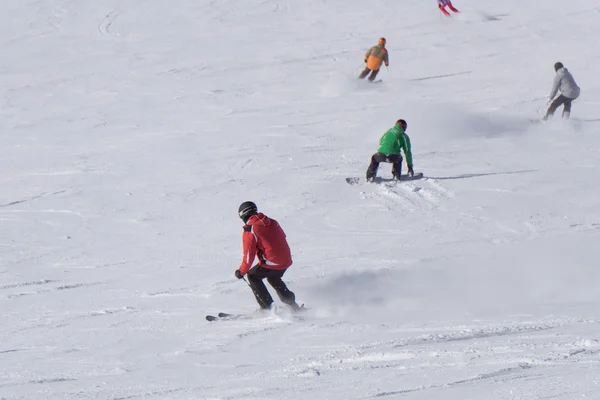 Lyžaři a snowboardisté se po svahu dolů. — Stock fotografie