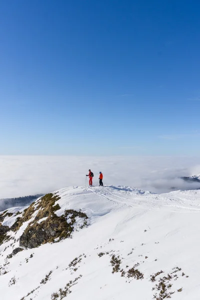 Due sciatori in cima alla montagna sopra le nuvole — Foto Stock