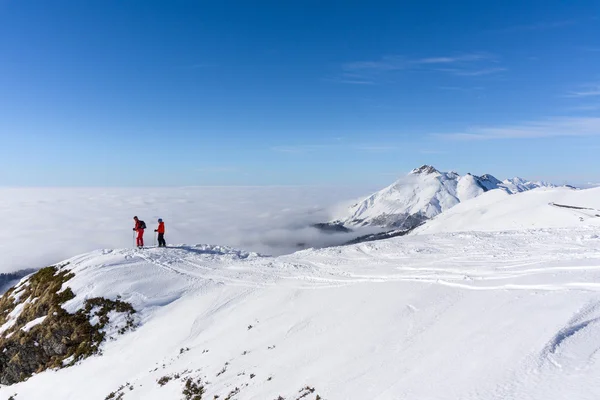 Dos esquiadores en la cima de la montaña sobre las nubes —  Fotos de Stock