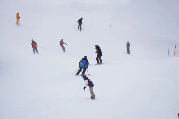 Skiers and snowboarders going down the slope. — Stock Photo, Image