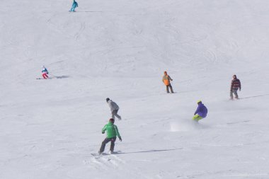 kayakçı ve snowboard düşkünleri yokuş aşağı gidiyor.