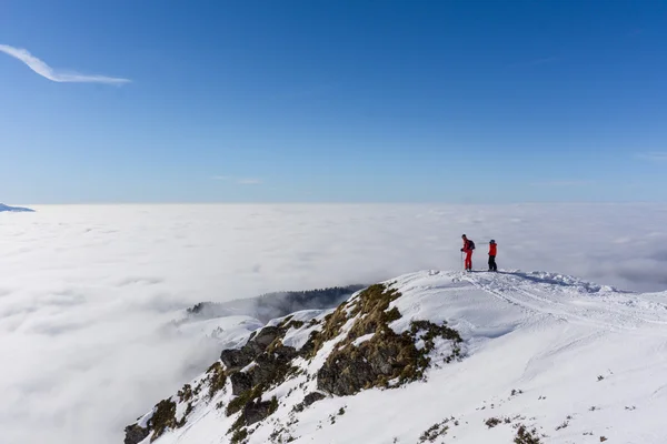 Two skiers on top of mountain above the clouds — Stock Photo, Image