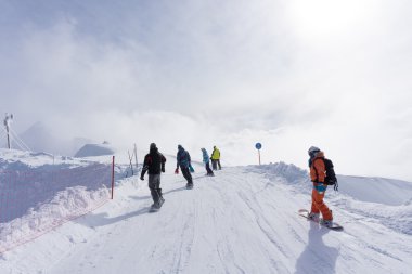 kayakçı ve snowboard düşkünleri yokuş aşağı gidiyor.
