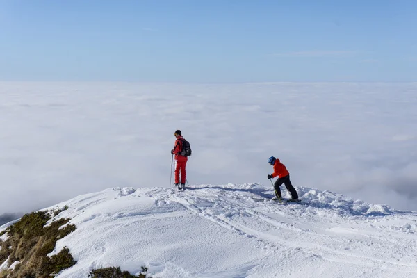 Due sciatori in cima alla montagna sopra le nuvole — Foto Stock