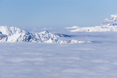 Dağlara ve bulutların üstündeki mavi gökyüzüne bak