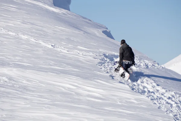 Snowboarder escalando uma montanha nevada — Fotografia de Stock