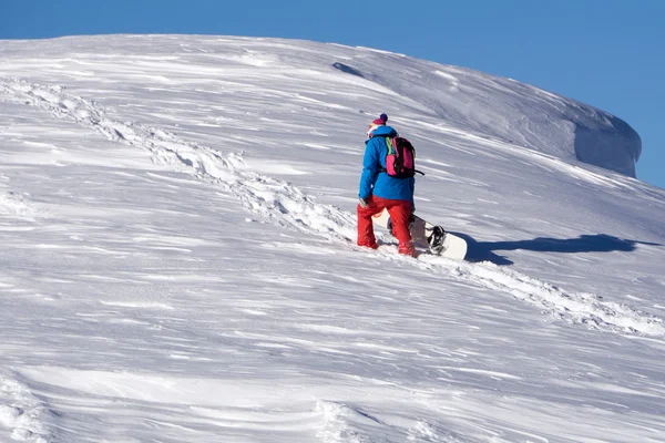 Snowboarder escalando uma montanha nevada — Fotografia de Stock