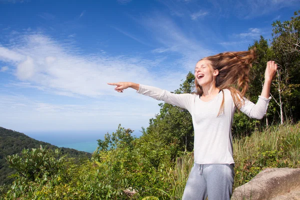 Meisje staat op een heuveltop punten in de verte — Stockfoto