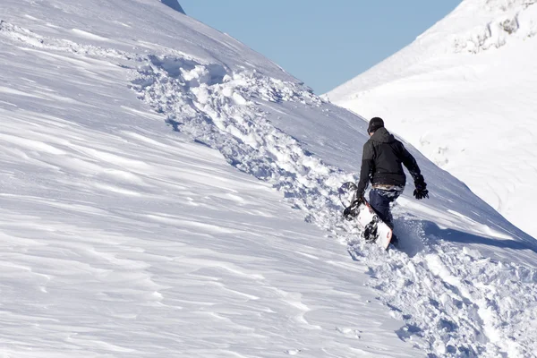 Snowboardåkare klättra en snöig berg — Stockfoto