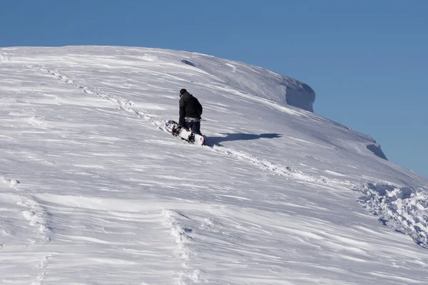 Snowboarder erklimmt einen verschneiten Berg — Stockfoto