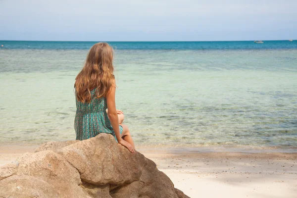 Mädchen in Kleid sitzt auf einem Felsen am Meer — Stockfoto