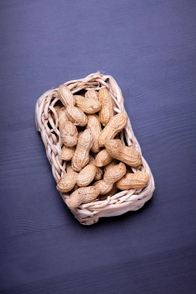 Peanuts isolated in basket on dark background — Stock Photo, Image