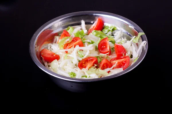 Fresh salad in a metal plate on black — Stock Photo, Image