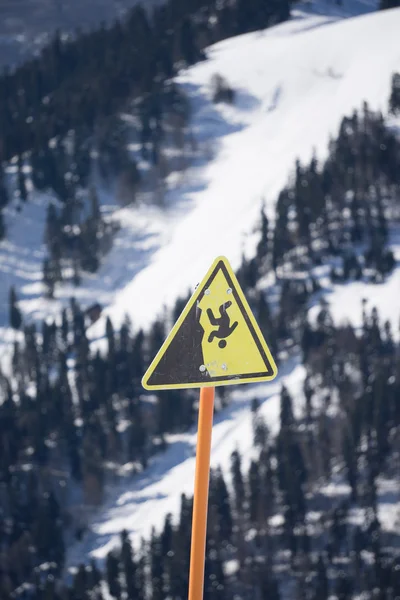 Perigo penhasco íngreme sinal de montanha, montanhas e céu nublado — Fotografia de Stock