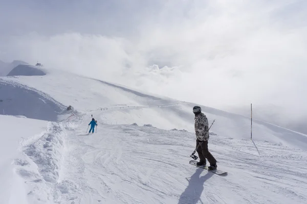Skifahrer und Snowboarder auf der Piste. — Stockfoto