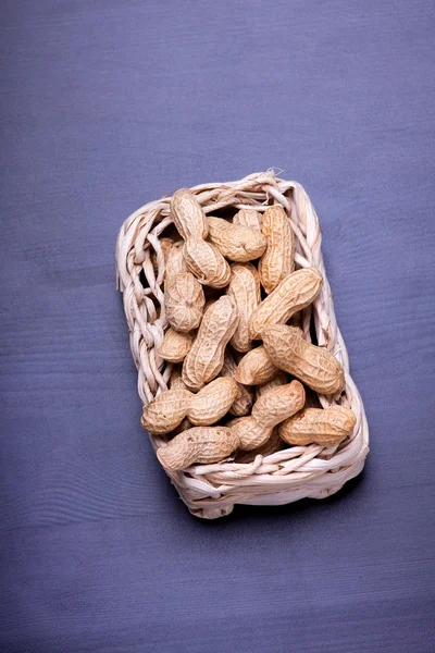 Peanuts isolated in basket on dark background — Stock Photo, Image