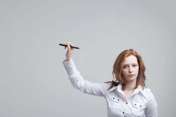 Молода жінка з ручкою на сірому фоні — стокове фото