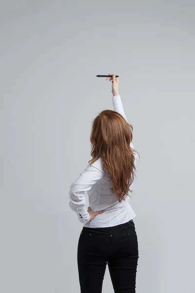 Jovem mulher com caneta sobre fundo cinza — Fotografia de Stock