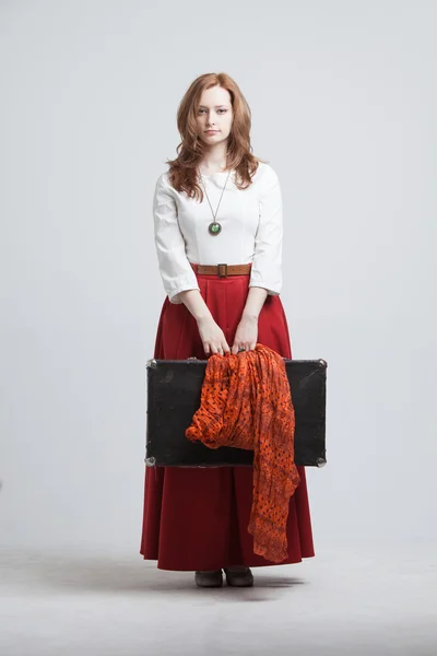 Женщина в винтажной красной юбке с чемоданом — стоковое фото