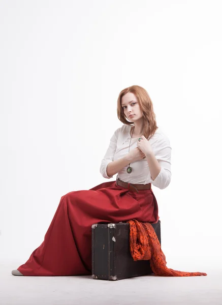 Femme assise sur une valise, isolée, fond blanc — Photo