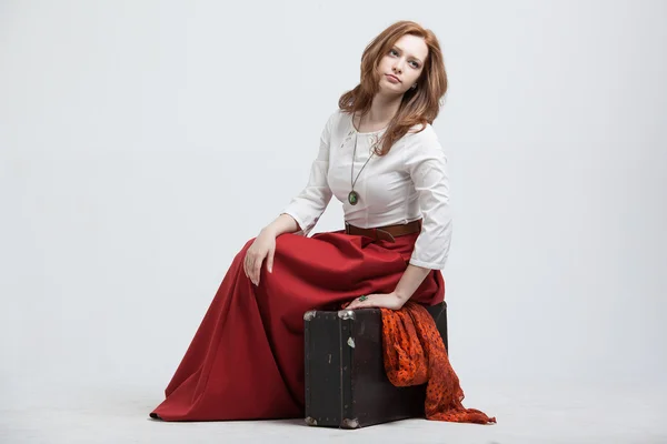 Donna seduta su valigia, isolata, sfondo bianco — Foto Stock