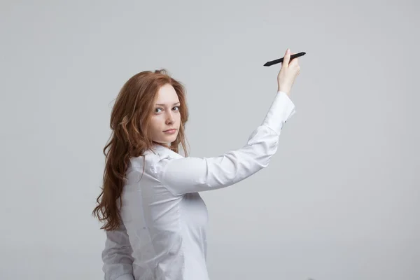 Young woman with pen on grey background — Stock Photo, Image