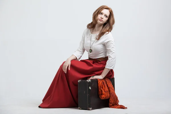 Woman sitting on suitcase, isolated, white background — Stock Photo, Image