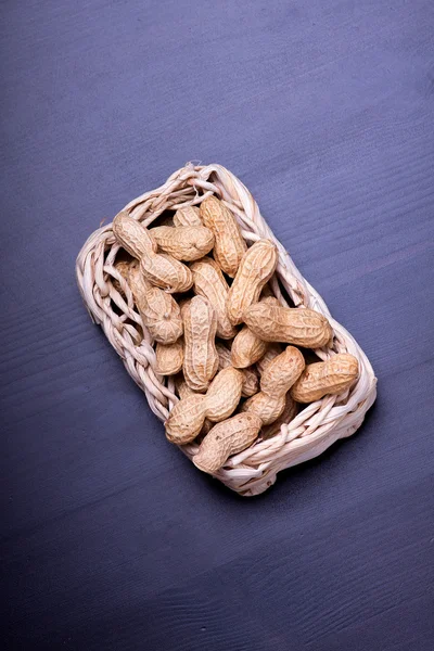 Cacahuètes isolées dans le panier sur fond sombre — Photo