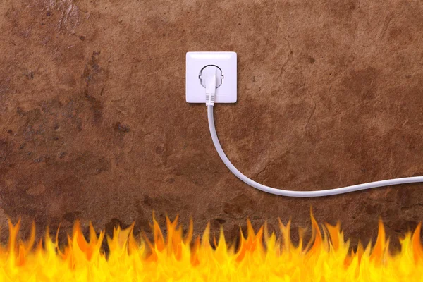 Pared grunge con una toma de corriente eléctrica y fuego — Foto de Stock