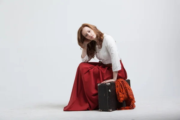 Женщина сидит на чемодане, изолированный, белый фон — стоковое фото