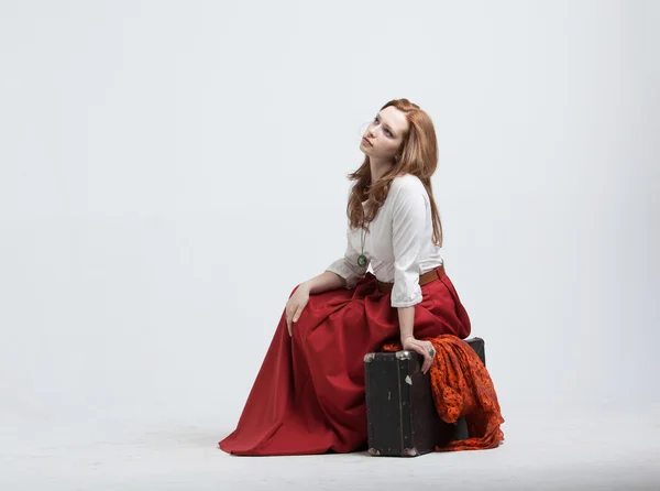 Femme assise sur une valise, isolée, fond blanc — Photo