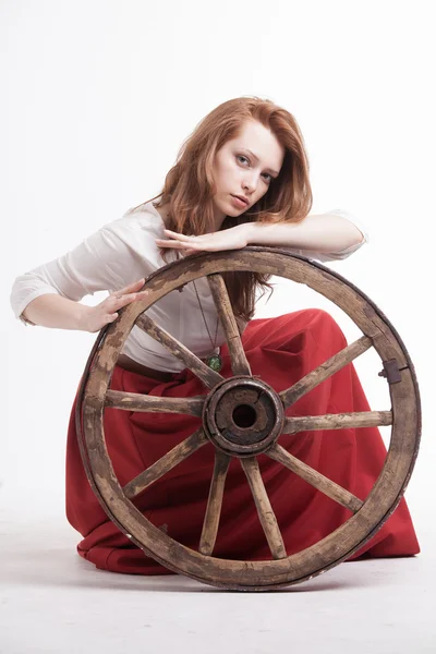 Mujer joven con una vieja rueda de carreta — Foto de Stock