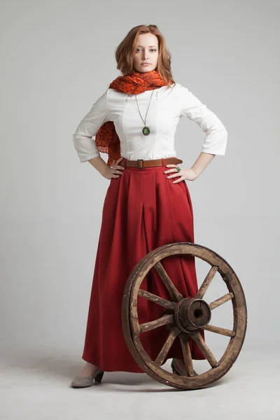 Woman in long red skirt  standing near wheel of the cart — Stock Photo, Image